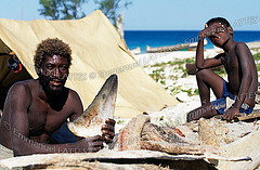 Pêcheur de requin et son fils (Morombe, Madagascar). L'homme exhibe un aileron qu'il fera sécher au soleil avant de le vendre à des grossistes chinois.